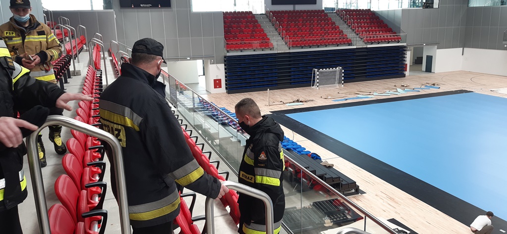 Strażacy przeprowadzają rozpoznanie w środku hali sportowej.