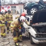 Strażacy podczas ćwiczeń na placu komendy wykonują dostęp do samochodu narzędziami hydraulicznymi.