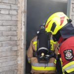 Strażacy podczas ćwiczeń wchodzą do zadymionego budynku.