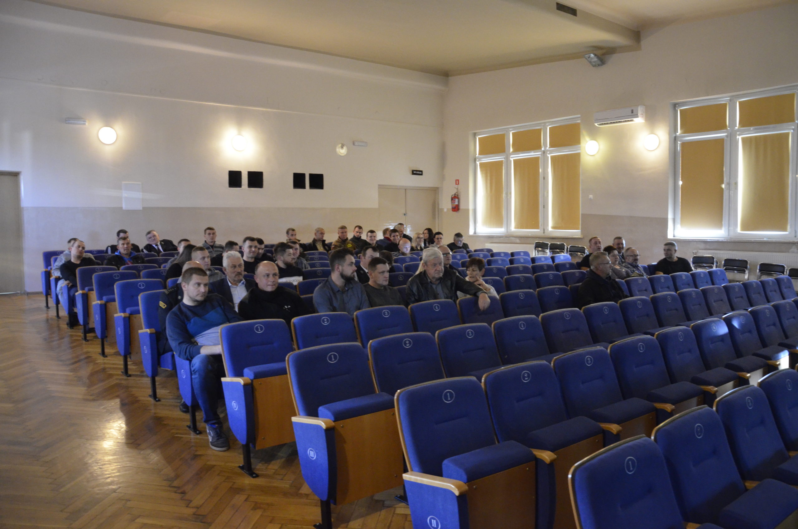 Przedstawiciele jednostek Ochotniczych Straży Pożarnych z terenu powiatu puławskiego siędzą na fotelach podczas spotkania.