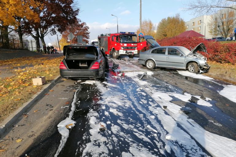 Dwa uszkodzone samochody osobowe podczas zderzenia czołowego na ulicy Gościńczyka w Puławach. W tle samochód strażacki.